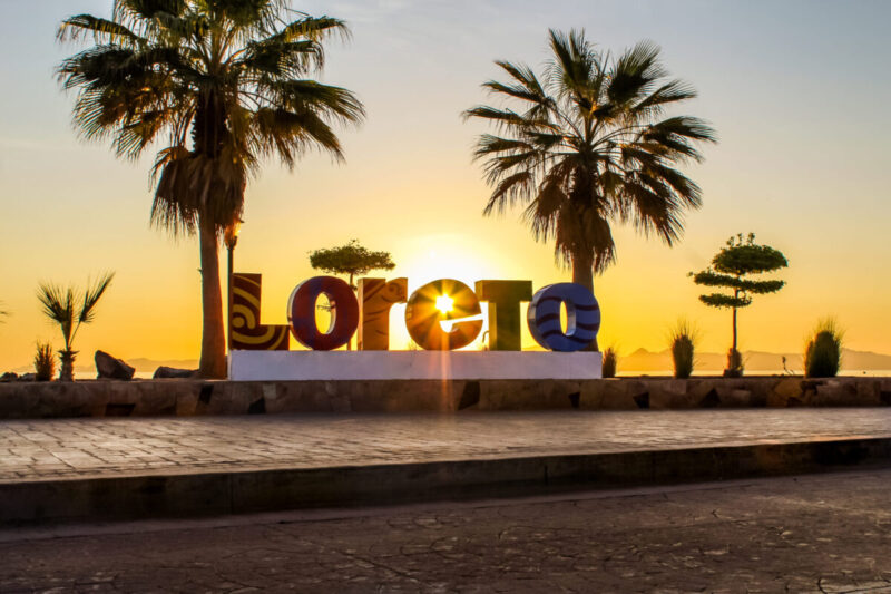 Loreto waterfront sign at sunrise with Sea of Cortez light