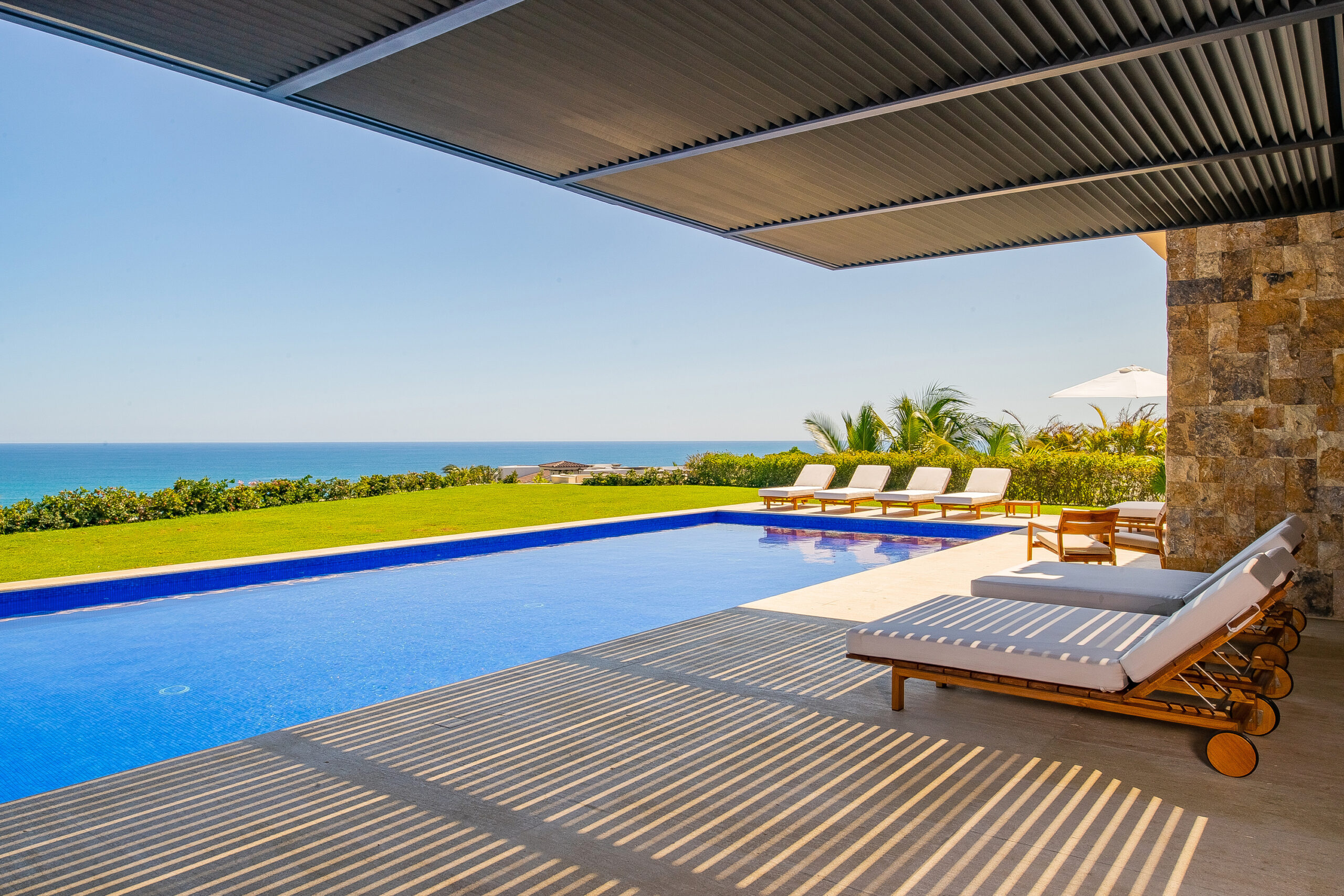 Villa Saguaro beautiful patio with lounge chairs by the pool and ocean views in Puerto Los Cabos