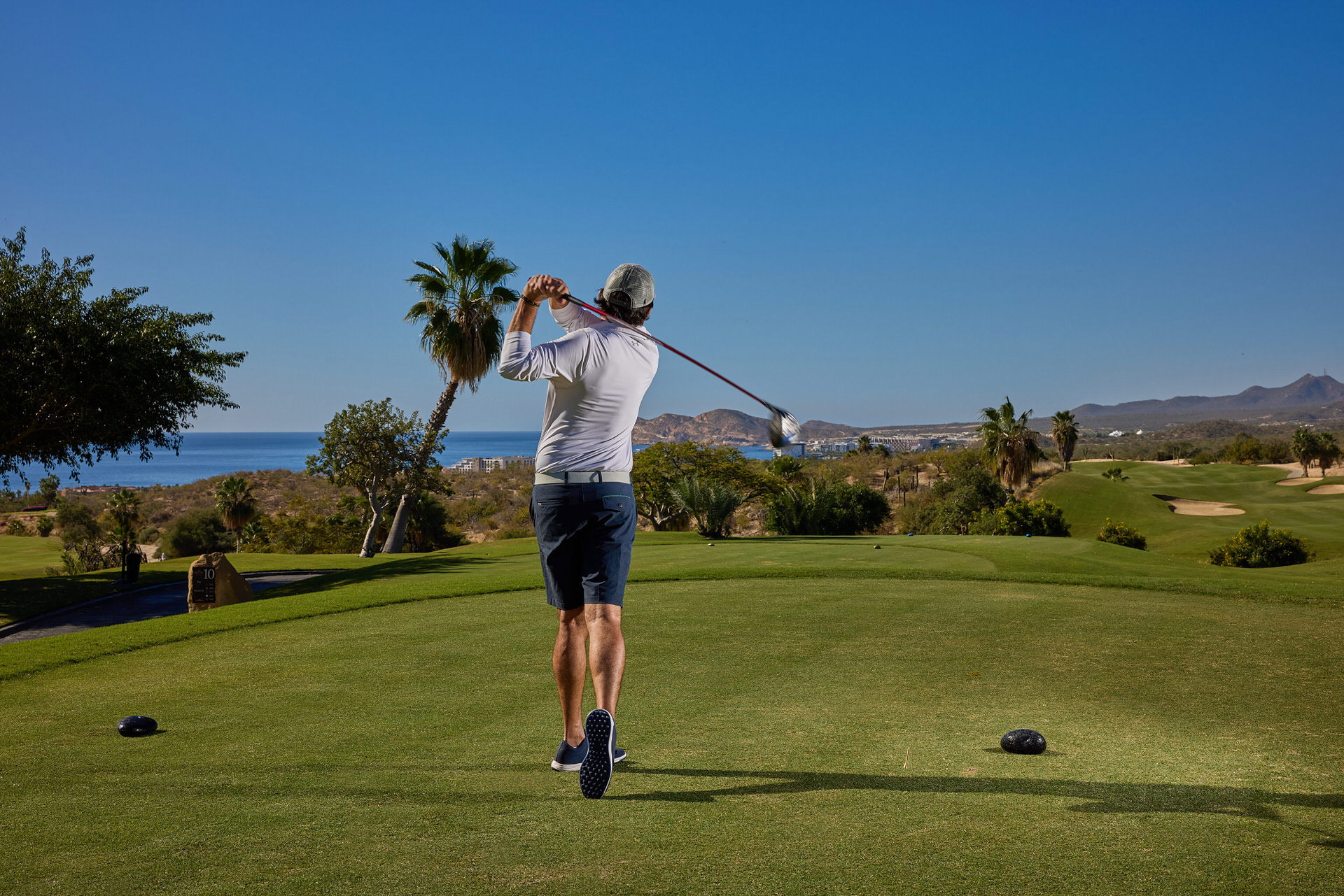 Golfer teeing off at Cabo Real Golf Club during a Cabo golf weekend
