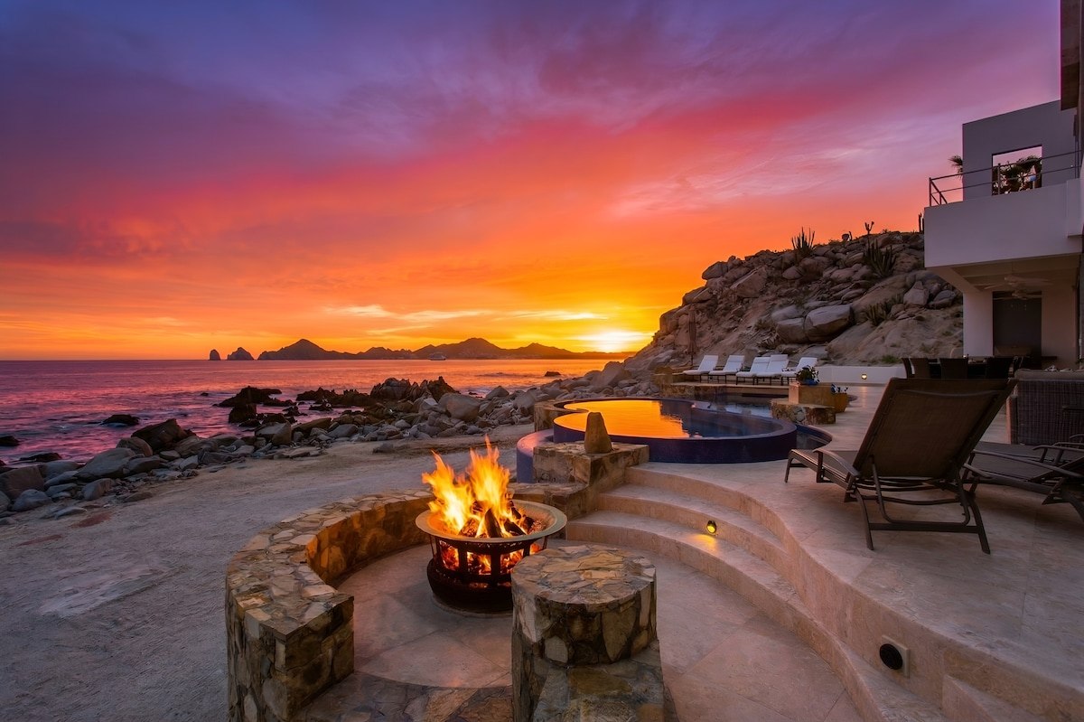Beachfront firepit glowing at sunset beside Casa Luna's pool in Cabo
